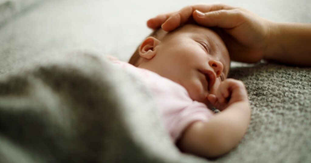 baby-sleeping-peacefully-while-mother-is-caressing-its-head-gently