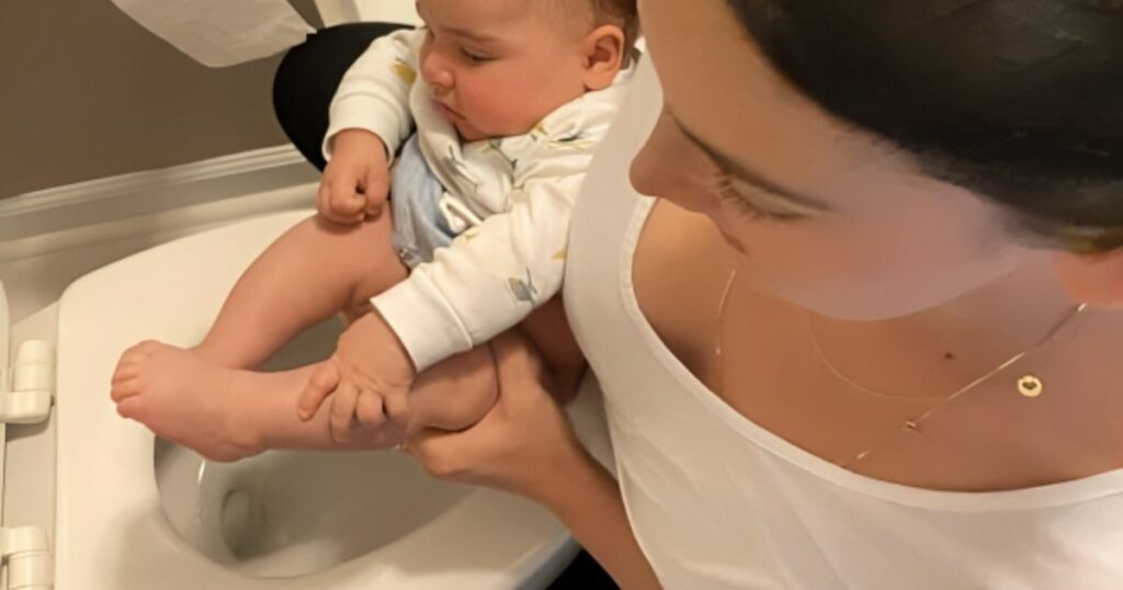 A mother holds her baby over a toilet, practicing elimination communication. This method involves recognizing and responding to the baby's cues for toileting.