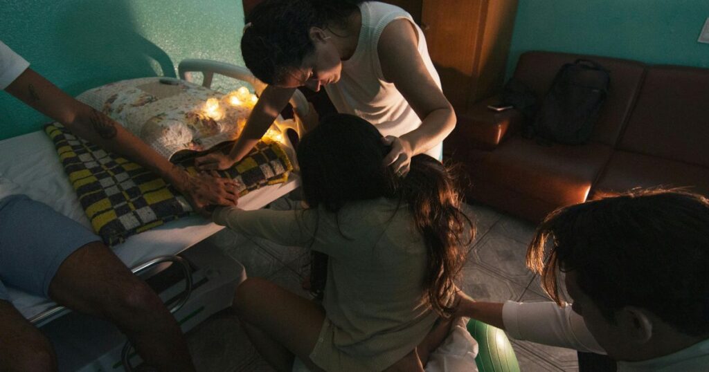 woman having an out of hospital birth supported by a midwife and family in a calm, peaceful environment at home