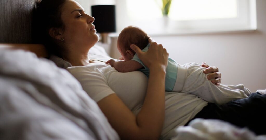 postpartum-mother-holding-her-newborn-baby-feeling-overwhelmed-and-tired