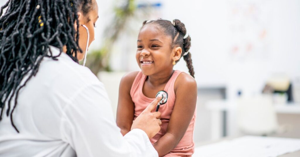 Pediatrician-using-a-stethoscope-to-check-a-smiling-young-girls-heartbeat