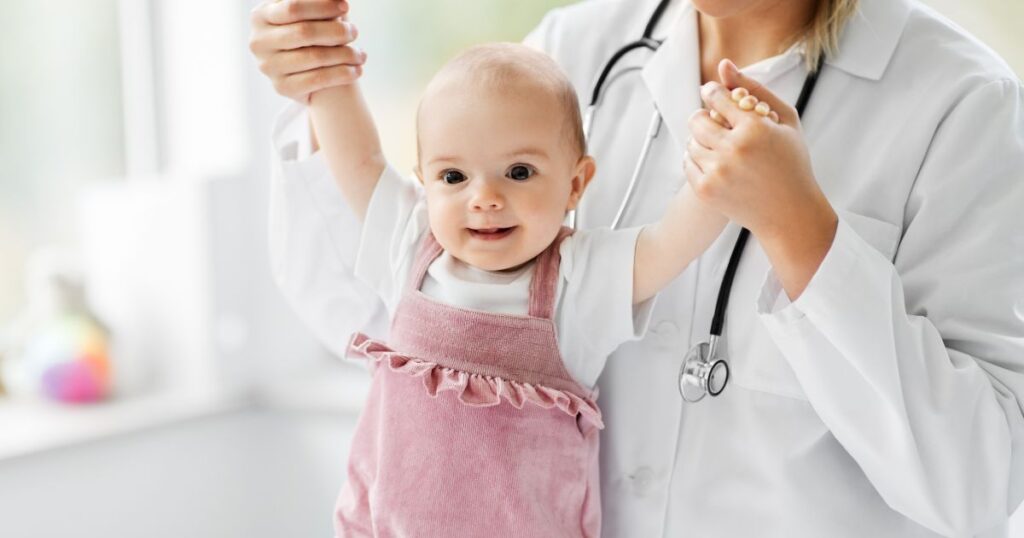 Happy-baby-being-supported-by-a-pediatrician-during-a-check-up-with-stethoscope-visible