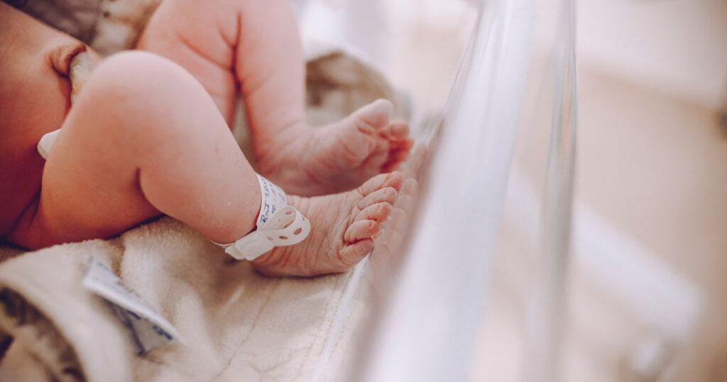 newborn baby in hospital bassinet with visible identification band on the ankle