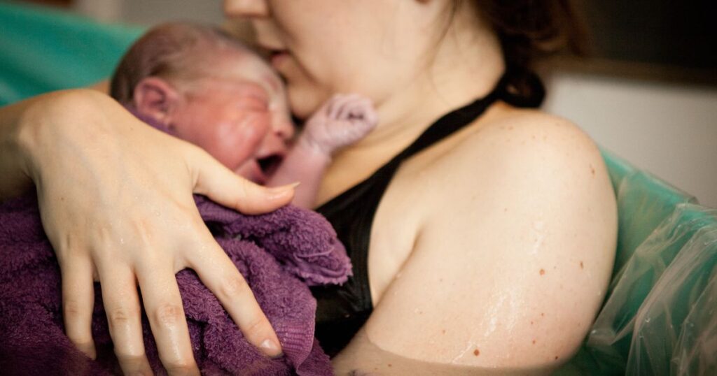 newborn wrapped in towel after a water birth at home in charlotte, NC