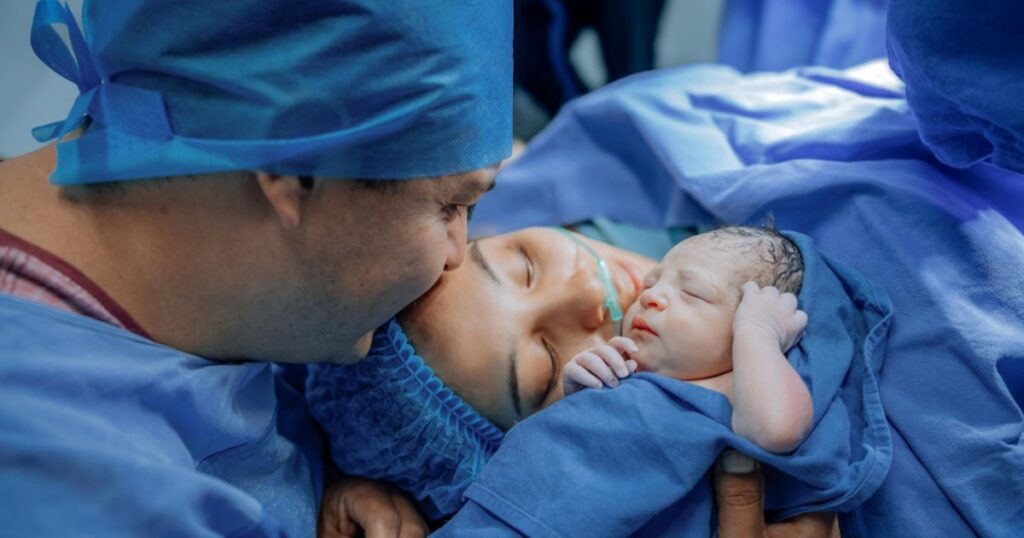 mother and father in scrubs holding their newborn baby right after giving birth in a hospital