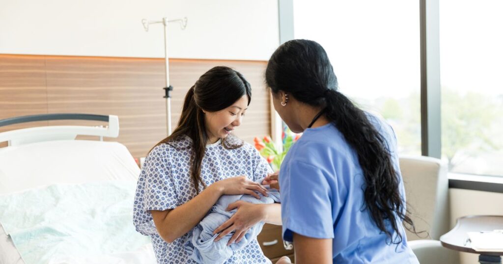 Mom holding her baby with a nurse helping