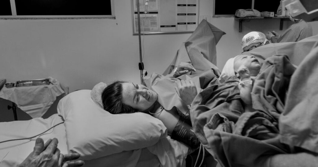 newly postpartum mother being handed her newborn baby after giving birth in a hospital
