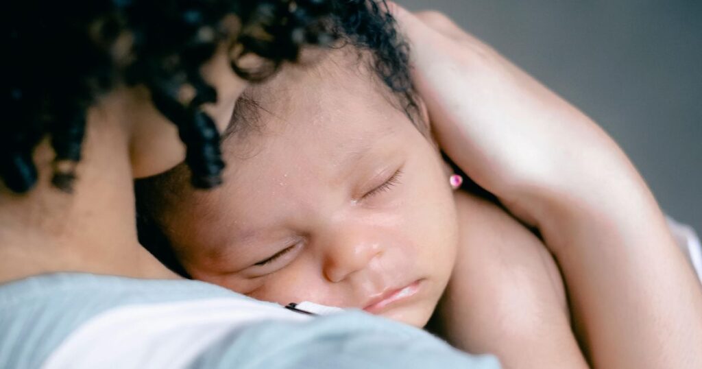 mother holding a sleeping baby with her hand gently on baby's head