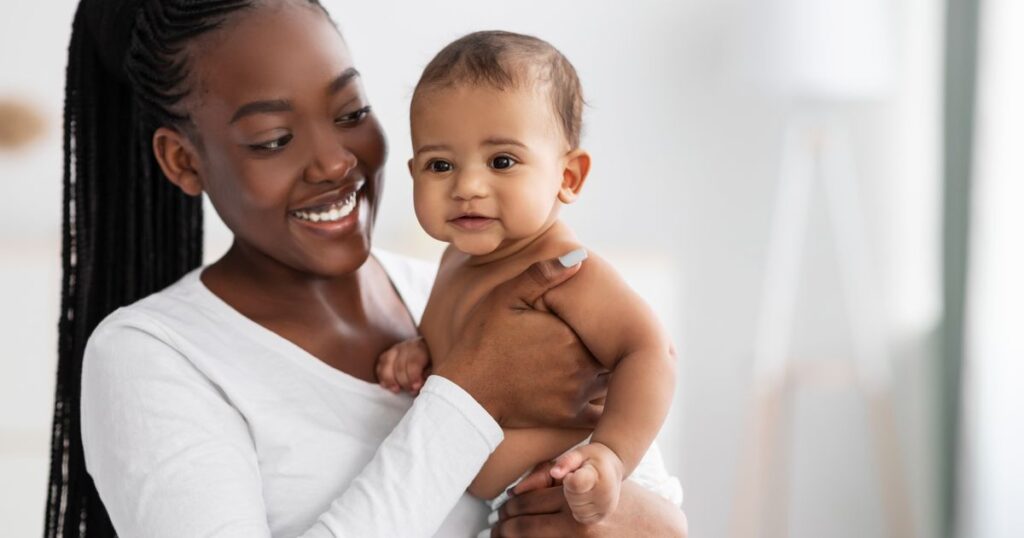 new mom holding her baby while smiling