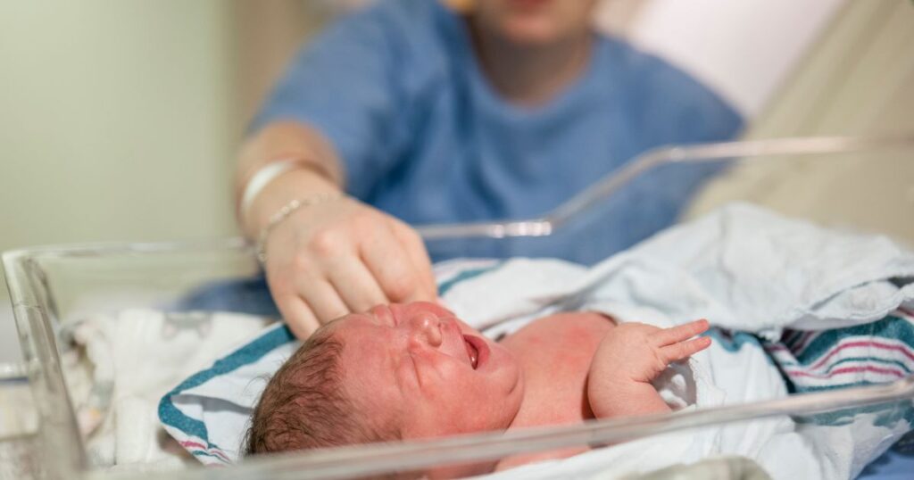 postpartum mother in hospital soothing her crying newborn baby