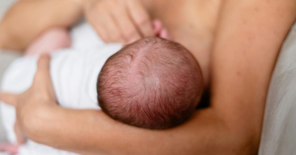 postpartum mom holding her baby while she is breastfeeding