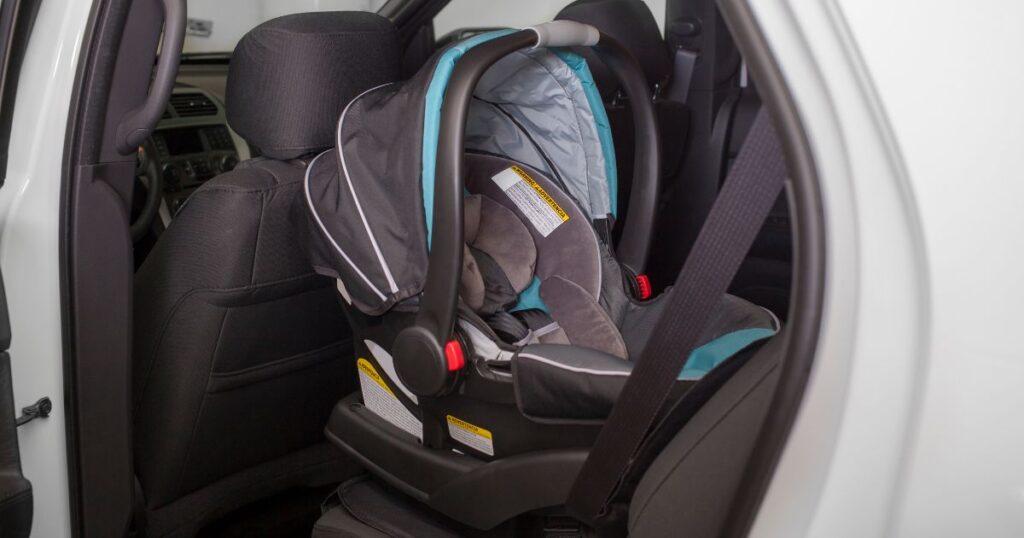 stock image of an empty, rear-facing  infant car seat installed in a car