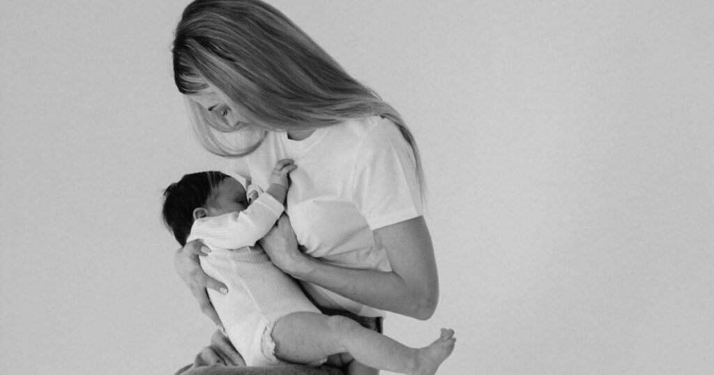 Breastfeeding mom with baby in black and white photo