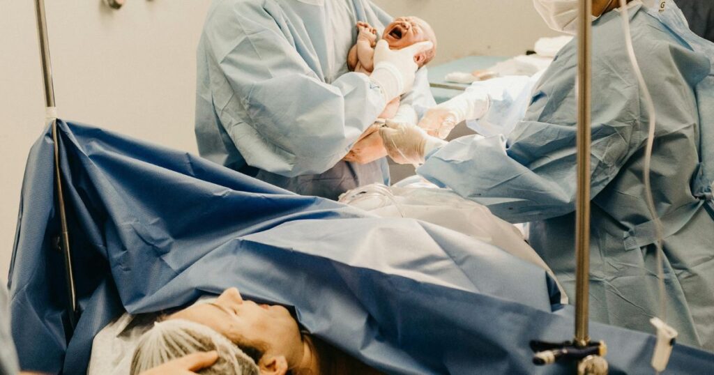 mother who has just given birth in a hospital looks up after doctors have just delivered her screaming baby